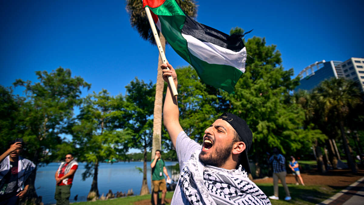 A protester chants while holding aloft the Palestinian flag