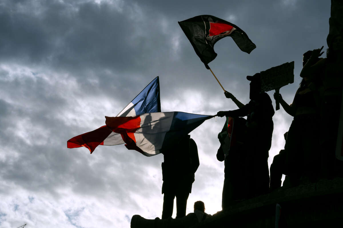 People wave the Antifascist and French flags at an outdoor rally