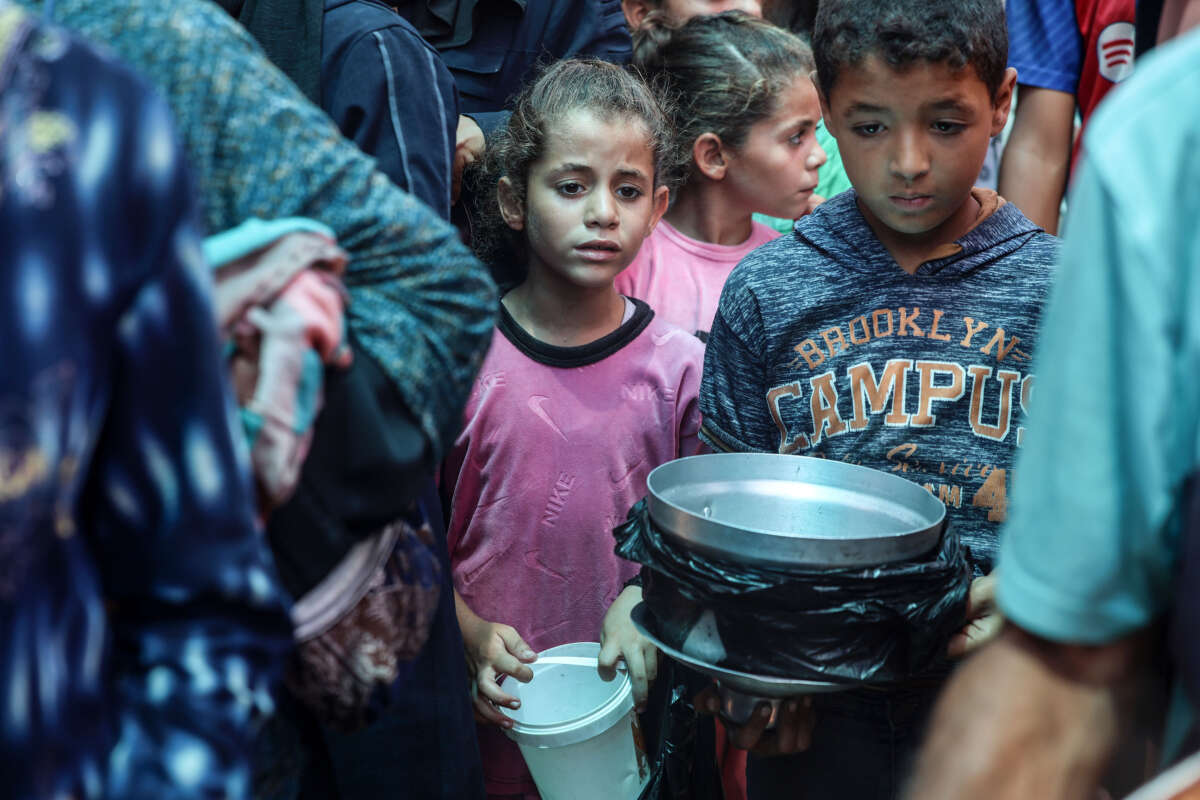 Palestinians line up for meal rations at a communal food distribution point in Deir al-Balah in the besieged Gaza Strip on June 10, 2024.