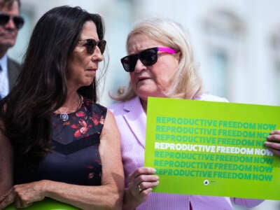 Rep Sylvia Garcia holds a sign reading "REPRODUCTIVE FREEDOM NOW" while speaking quietly to Teresa Leger Fernandez, standing beside her