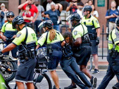 Cops drag a black-clad protester away