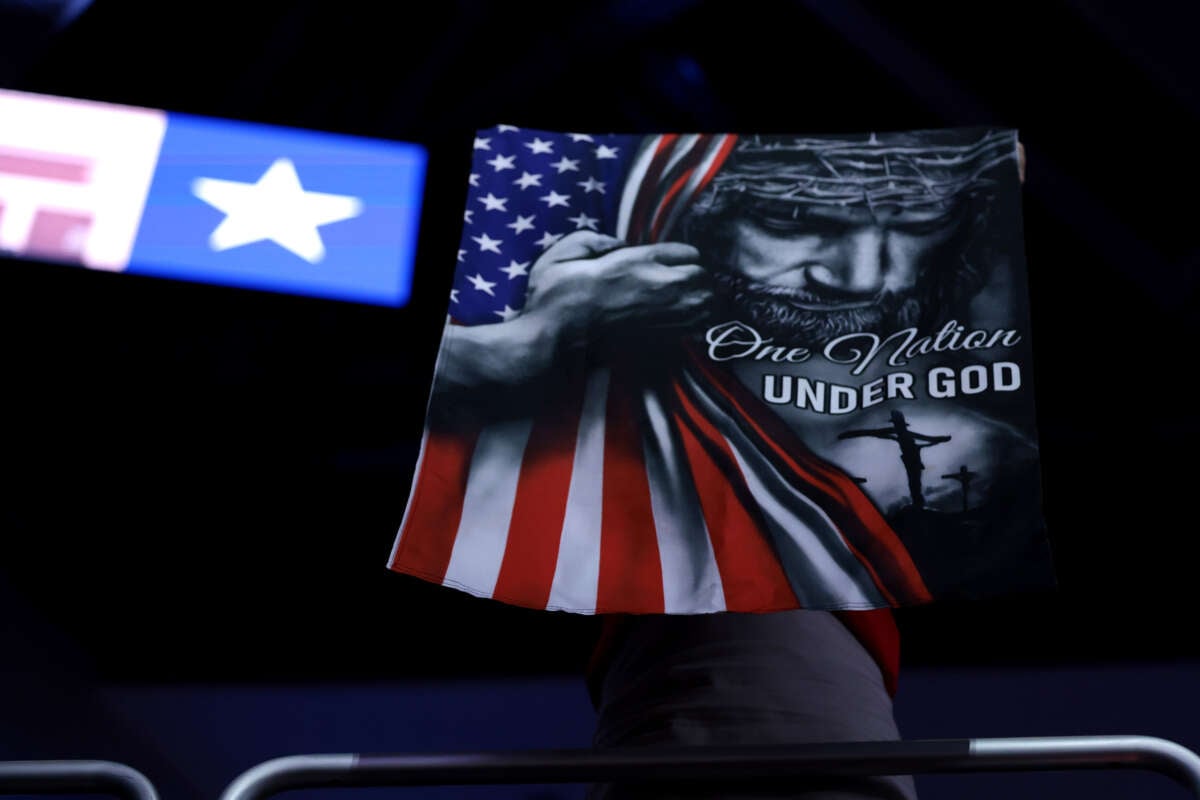 A banner of Republican Jesus Christ clutching a U.S. flag with the text "ONE NATION UNDER GOD" is hung on a wall