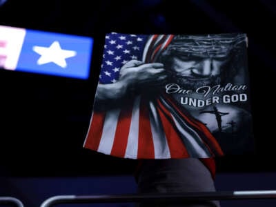 A banner of Republican Jesus Christ clutching a U.S. flag with the text "ONE NATION UNDER GOD" is hung on a wall