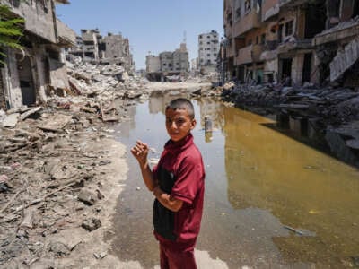A Palestinian boy looks over as he stands on the rubble of buildings destroyed in previous Israel bombardment, on the edge of a pool of stagnant water in Khan Yunis in the southern Gaza Strip on July 19, 2024.