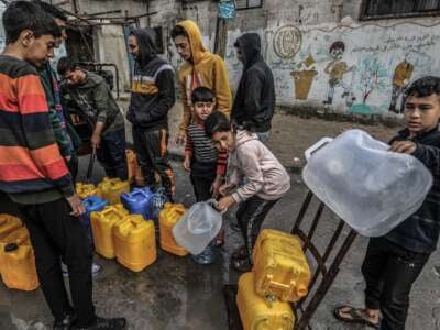 Palestinian children wait with jerry cans to fill them with drinking water in Rafah on February 19, 2024.