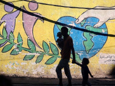 A family walks past a battered mural of the Earth in the shape of a heart
