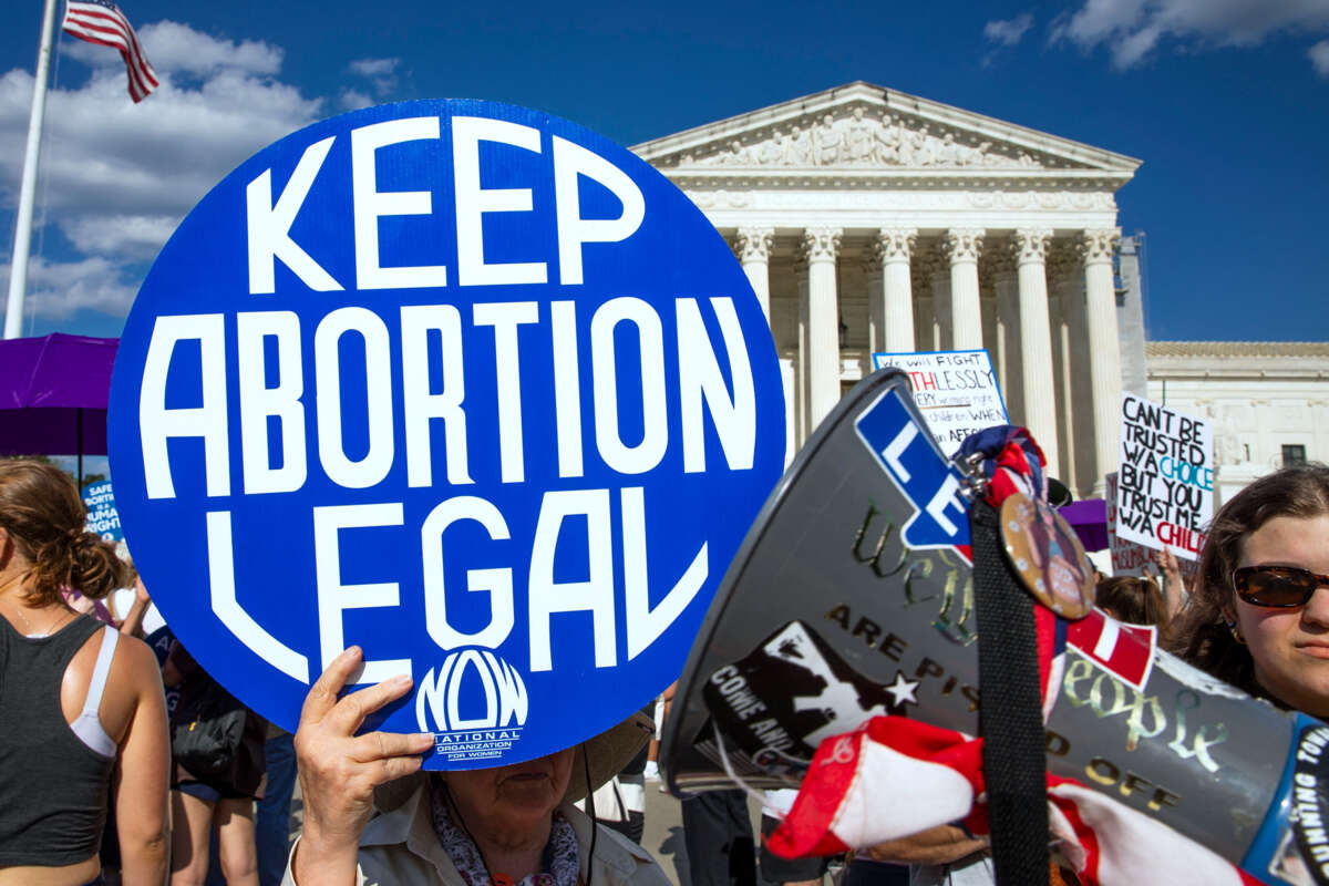 A protester holds a blue, circular sign reading "KEEP ABORTION LEGAL" during a protest on the steps of the Supreme Court of the United States