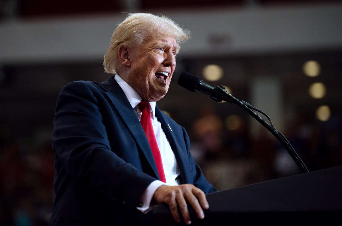 Donald Trump shouts into a microphone at a podium