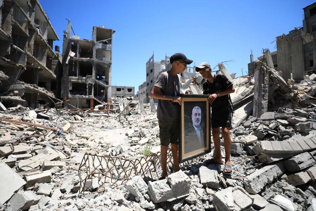 Palestinians carry the portrait of Hamas political bureau chief Ismail Haniyeh, who was assassinated, as they stand on the debris of a destroyed building that belonged to him, following the Israeli attack in Al-Shati refugee camp of Gaza City, Gaza, on July 31, 2024.