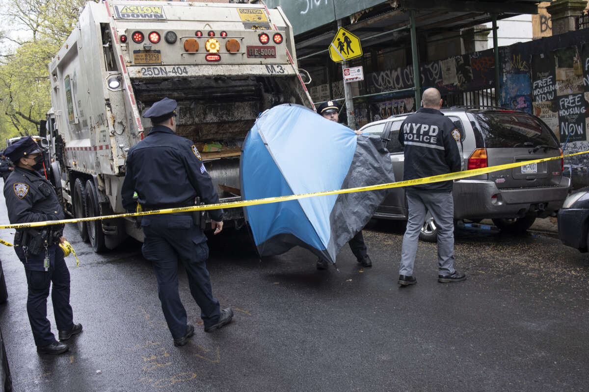 Police enforce a sweep of a homeless encampment, throwing tents and other possessions of the homeless in a trash truck, on May 4, 2022, in the East Village neighborhood of New York City.