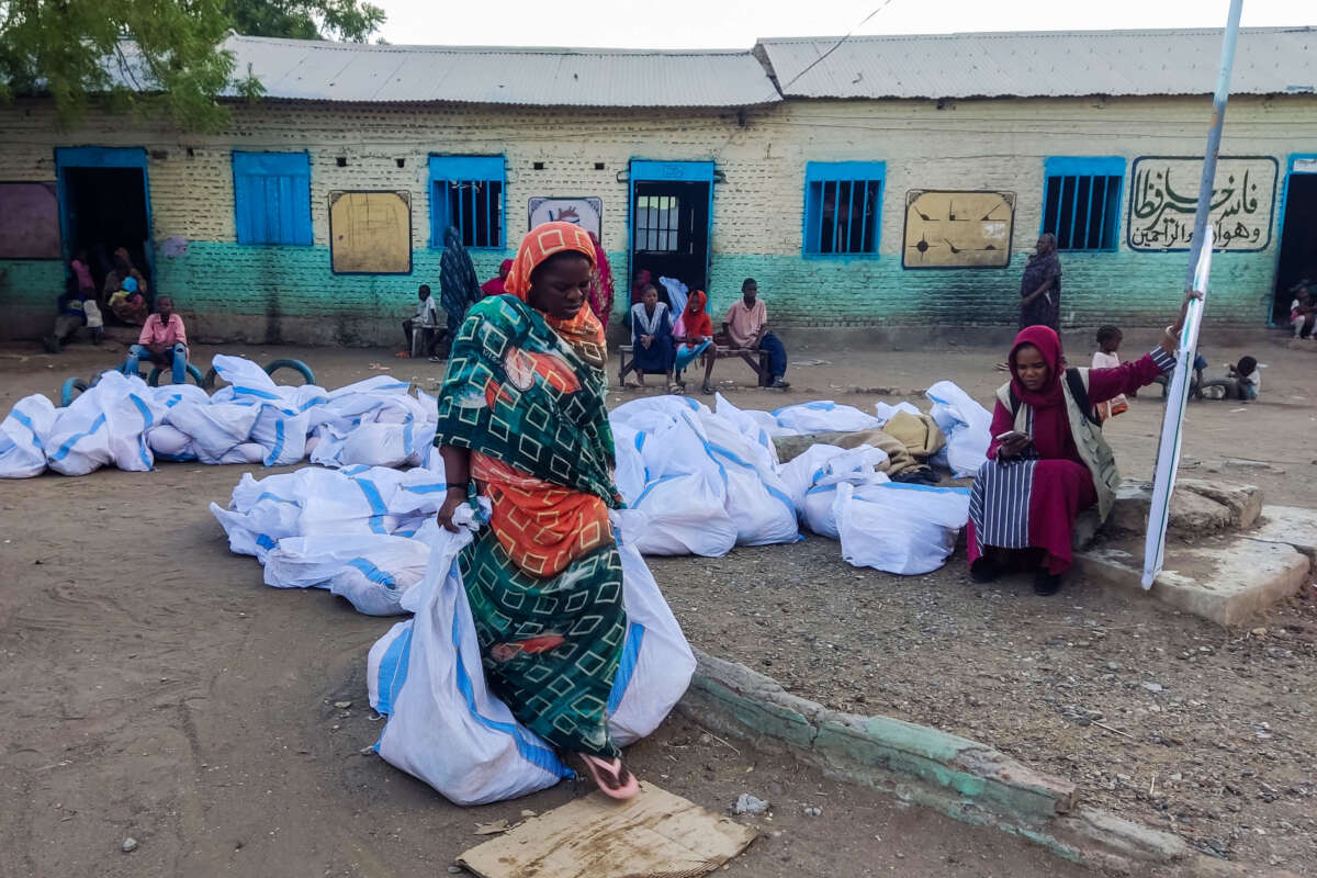 An internally displaced woman carries aids in sacks after collecting from a group at a camp in Gadaref on May 12, 2024.