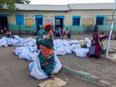 An internally displaced woman carries aids in sacks after collecting from a group at a camp in Gadaref on May 12, 2024.