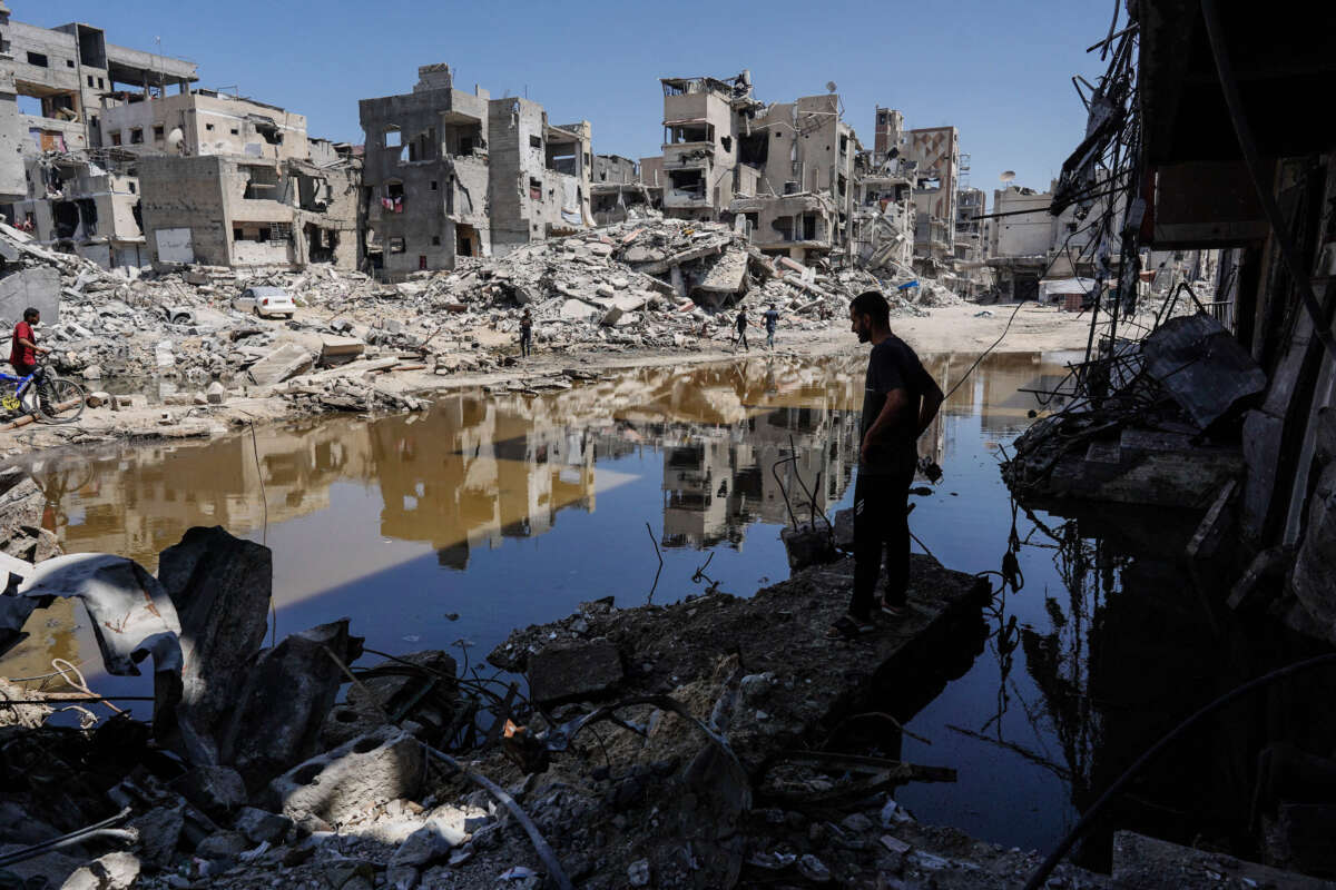 A Palestinian stands on the rubble of destroyed buildings as he looks at the a pool of stagnant water in Khan Yunis in the southern Gaza Strip on July 19, 2024.