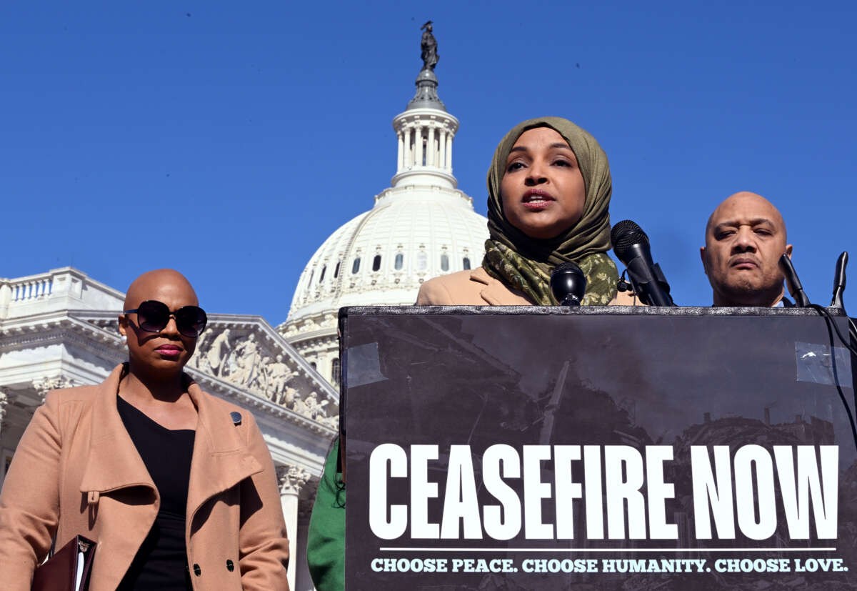 Ilhan Omar stands in front of the U.S. Capitol and behind a podium reading "CEASEFIRE NOW" as she speaks