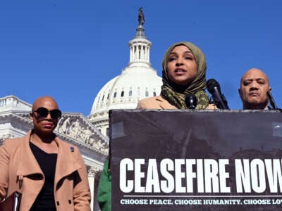 Ilhan Omar stands in front of the U.S. Capitol and behind a podium reading "CEASEFIRE NOW" as she speaks