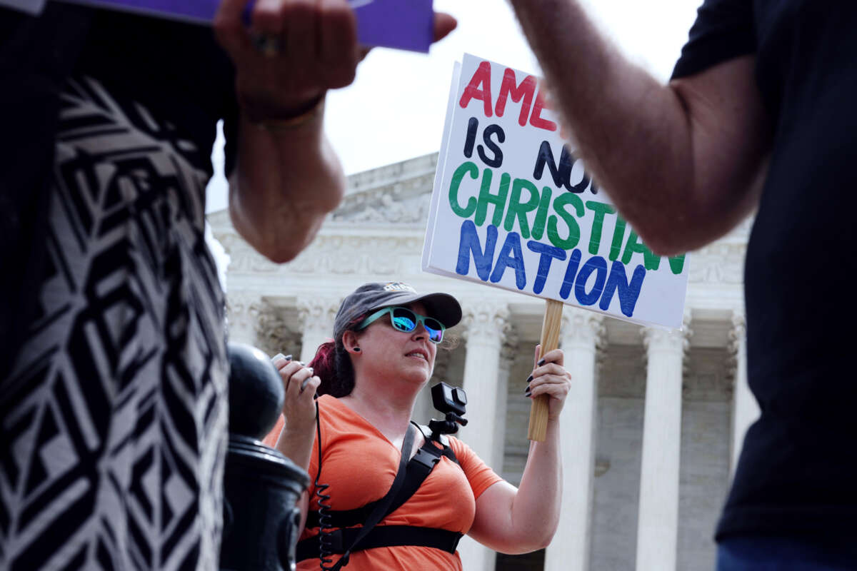 A protester holds a sign reading "AMERICA IS NOT A CHRISTIAN NATION" outside of the supreme court of the united states