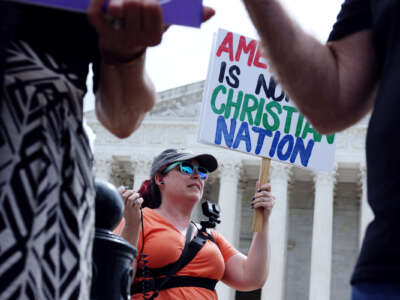 A protester holds a sign reading "AMERICA IS NOT A CHRISTIAN NATION" outside of the supreme court of the united states