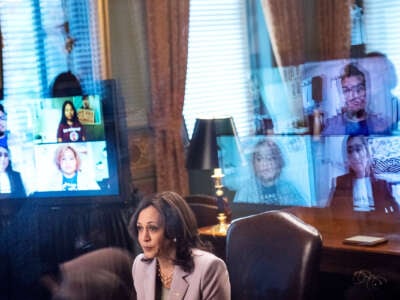 Kamala Harris is seen beside the reflected screens of several DACA recipients with whom she is in audience