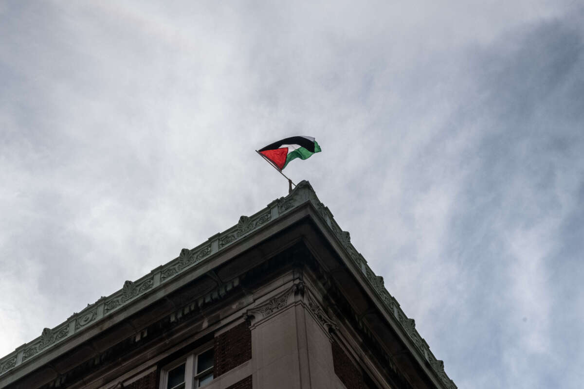 A protester flies a Palestinian flag from on top of Hamilton Hall as part of a pro-Palestinian encampment on Columbia University campus on April 30, 2024, in New York City.