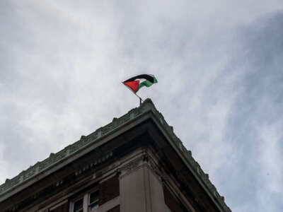 A protester flies a Palestinian flag from on top of Hamilton Hall as part of a pro-Palestinian encampment on Columbia University campus on April 30, 2024, in New York City.