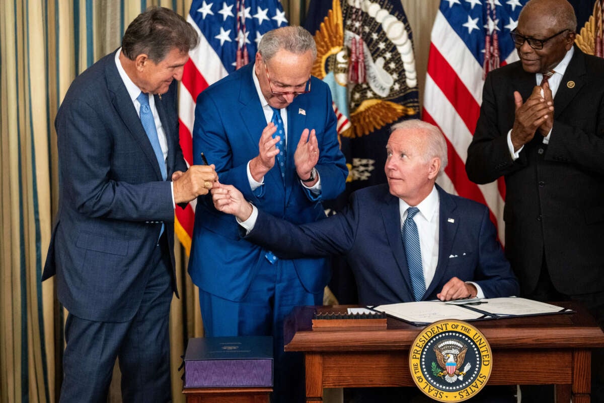 President Joe Biden, center, hands the pen used to sign H.R. 5376, the Inflation Reduction Act of 2022 into law, to Sen. Joe Manchin in the State Dining Room of the White House on August 16, 2022, in Washington, D.C.