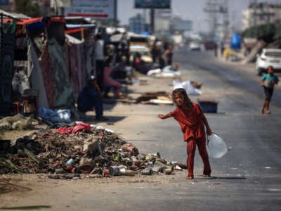 A Palestinian girl carries water at a makeshift roadside refugee camp in Deir el-Balah in the central Gaza Strip on August 13, 2024.