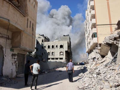 Palestinians watch as smoke rises from a building hit by an Israeli strike after a warning from the army to its occupants to evacuate the premises, in the Rimal neighbourhood of central Gaza City on August 21, 2024.