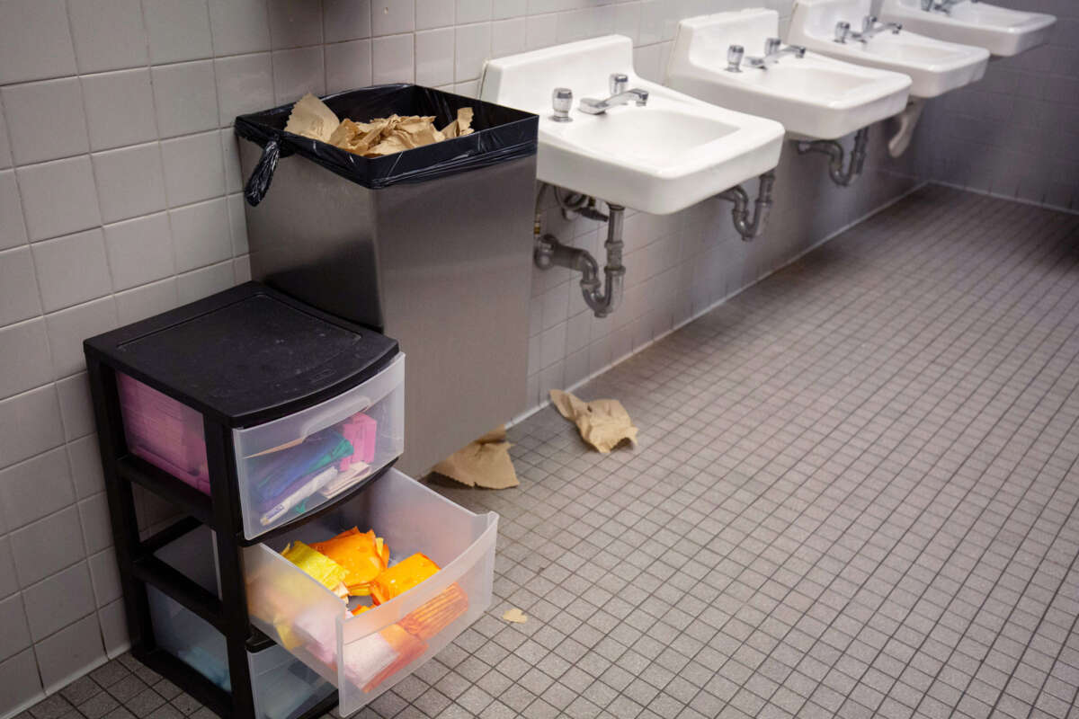 The interior of a public bathroom with a small plastic file cabinet containing menstrual products