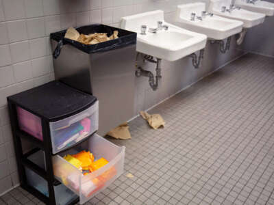 The interior of a public bathroom with a small plastic file cabinet containing menstrual products