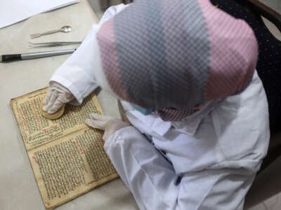 A Palestinian woman, who specializes in conservation, restoring and digitizing manuscripts and rare books, works at a laboratory within the Eyes on Heritage institute, in Gaza City, on July 10, 2023.