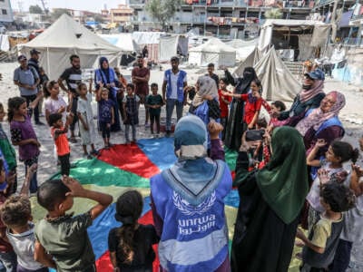 Officials of United Nations Relief and Works Agency for Palestine Refugees in the Near East (UNRWA) play with the children who were adversely affected by Israeli attacks near a school for Palestinian refugees in Khan Yunis, Gaza, on July 4, 2024.