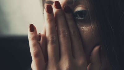 Close-up of a woman in distress covering her face in her hands