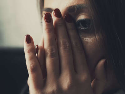 Close-up of a woman in distress covering her face in her hands