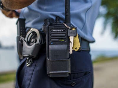 A Chicago police officer stands with a police radio near Oak Street Beach on August 18, 2022, in Chicago, Illinois.