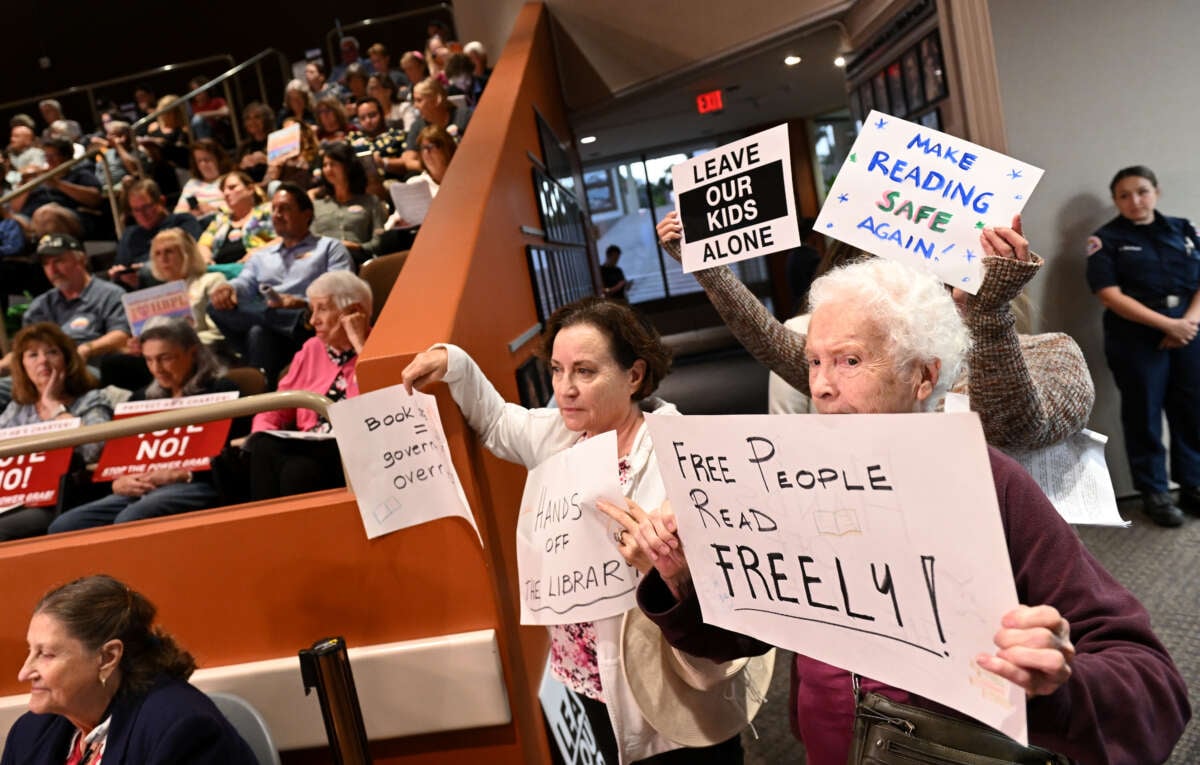 Opponents of a book ban hold signs during a Huntington Beach city council meeting on October 17, 2023, in Huntington Beach, California.