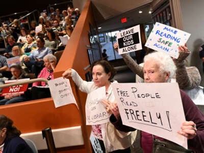 Opponents of a book ban hold signs during a Huntington Beach city council meeting on October 17, 2023, in Huntington Beach, California.