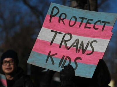 An activist holds a poster as hundreds of activists, allies and members of the transgender community gather at Dr. Wilbert McIntyre Park in Old Strathcona, in Edmonton, Alberta, Canada.