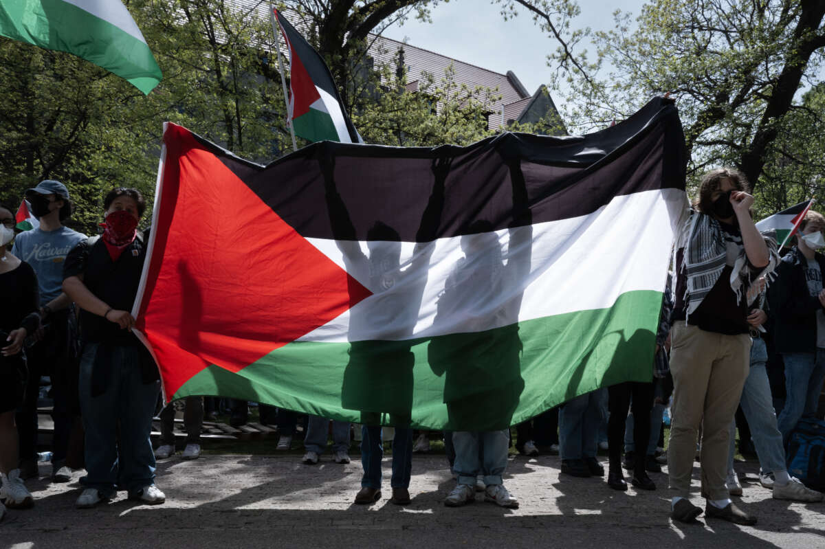 Demonstrators at a pro-Palestinian encampment hold up a Palestinian flag on the campus of the University of Chicago on May 3, 2024, in Chicago, Illinois.