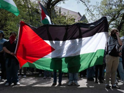 Demonstrators at a pro-Palestinian encampment hold up a Palestinian flag on the campus of the University of Chicago on May 3, 2024, in Chicago, Illinois.