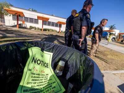 A notice of an impending encampment sweep is in a trash can as police keep an eye on city workers in Long Beach enforcing new policies regarding homeless encampments at Gumbiner Park on August 19, 2024, in Long Beach, California.