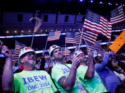 International Brotherhood of Electrical Workers members wave American flags during the final day of the Democratic National Convention on August 22, 2024, in Chicago, Illinois.