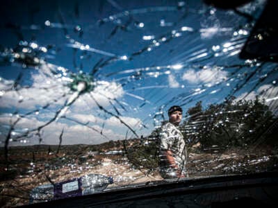 A Palestinian inspects a destroyed car that was bombed by Israeli forces, during a raid near the city of Jenin in the northern occupied West Bank, Palestine, on August 28, 2024.