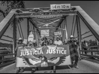 Farmworkers and their supporters occupy a highway bridge during their march demanding pay for working during wildfires.