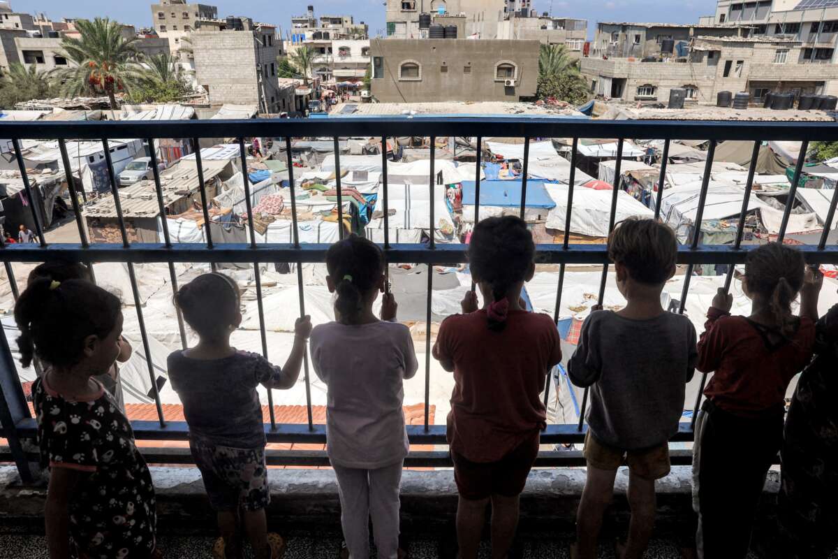 Children stand behind the rail of a hallway balcony outside classrooms sheltering people displaced by conflict at a school run by the UNRWA in Deir el-Balah in the central Gaza Strip on September 9, 2024.