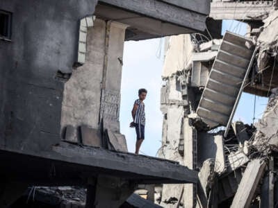 A young Palestinian stands near a building destroyed by an Israeli airstrike in the Nuseirat refugee camp in central Gaza Strip on August 23, 2024.