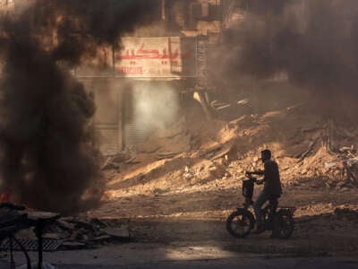 A Palestinian man stands in a devastated street near tyres set ablaze by youths in Jenin in the occupied West Bank on September 4, 2024, during an ongoing Israeli military raid.