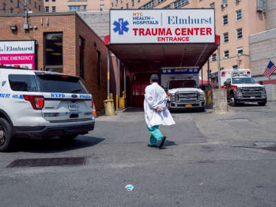 A lone medical worker walks towards a hospital