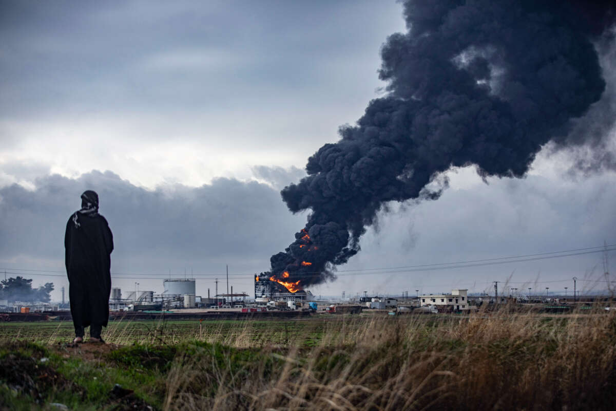 A person watches a building burning in the far distance