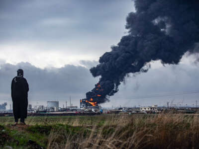 A person watches a building burning in the far distance