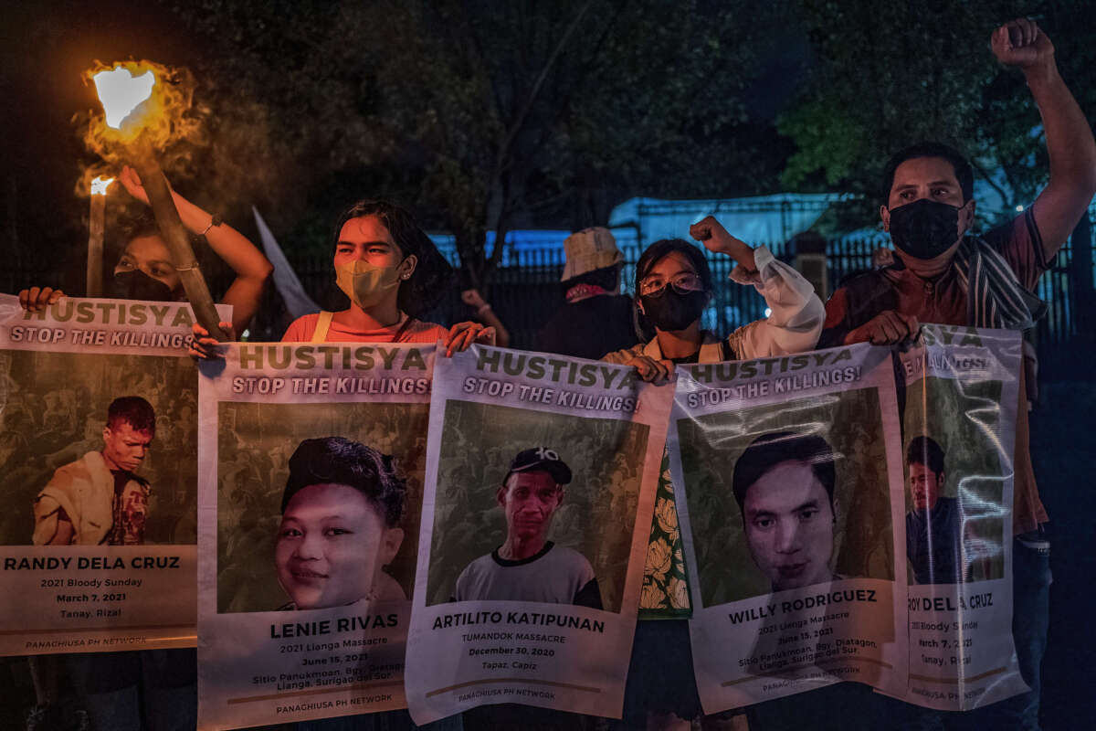 Activists hold up torches and portraits of slain Indigenous peoples and environmental defenders during a rally on November 10, 2022, in Quezon City, Metro Manila, Philippines.